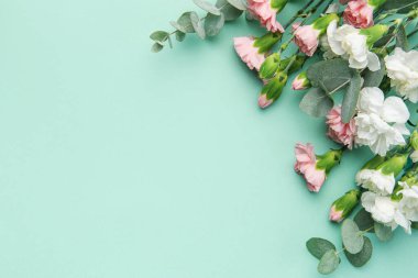 A bouquet of white and pink carnations with eucalyptus branches on a soft green background. Festive background.