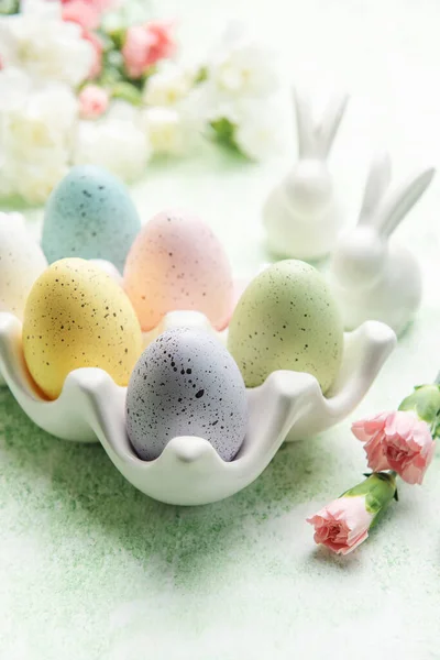 Easter decor. Colored Easter eggs on a ceramic stand and decorative rabbits. The concept of preparation for the celebration.