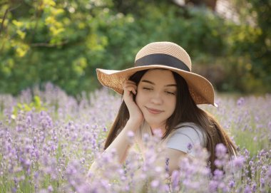 Beautiful young girl on lavender field. Sunset. Attractive young female outdoors.