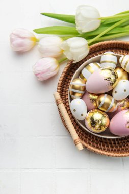 Easter golden eggs and pink tulips on white tile  background. Top view. Happy Easter composition. Greeting card.