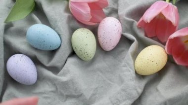 A woman's hand puts a colored Easter egg on the table. The concept of preparing for the Easter holiday