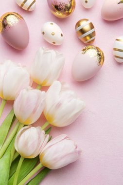 Easter golden eggs and pink tulips on pink  background. Top view. Happy Easter composition. Greeting card.