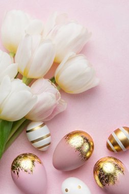 Easter golden eggs and pink tulips on pink  background. Top view. Happy Easter composition. Greeting card.