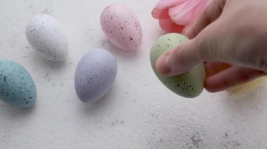 A woman's hand puts a colored Easter egg on the table. The concept of preparing for the Easter holiday