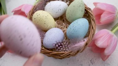 A woman's hand puts a colored Easter egg on the table. The concept of preparing for the Easter holiday