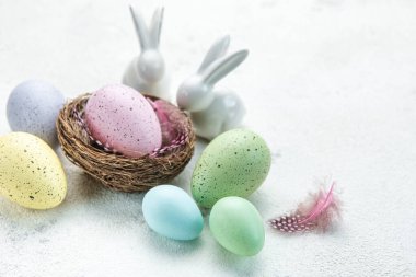Easter background. Easter eggs in nest with decor. Happy Easter concept. Eggs and rabbits on concrete backgroun
