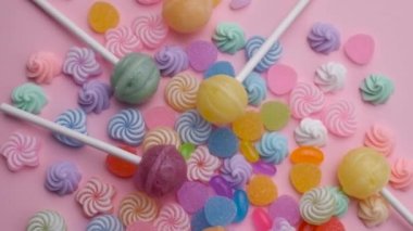 Çeşitli şeker lolipopları ve şekerler. Ağır çekim. Pembe arkaplanda video