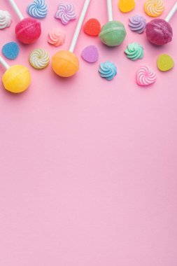 Colorful sweet lollipops and candies over pink background.  Flat lay, top view