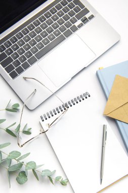 Modern white office desk table with laptop, notebook and other supplies. Blank copy space for  the text. Top view, flat lay.