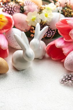 A bouquet of tulips, Easter bunnies and eggs on concrete background. Easter decoration and flowers.  Easter greeting card.