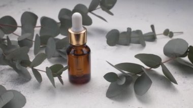 Gerekli yağı olan bir boru, beton zeminde okaliptüs yaprakları. Okaliptüs aromatik gerekli yağ. Doğal kozmetikler. Üst görünüm.