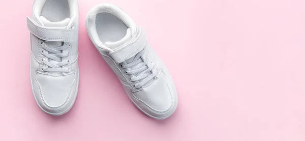 stock image White children's sneakers on a pink background with copy space. Banner.