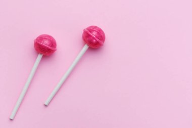 Colorful sweet lollipops over pink background.  Flat lay, top view