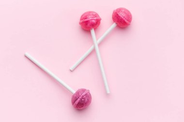Colorful sweet lollipops over pink background.  Flat lay, top view