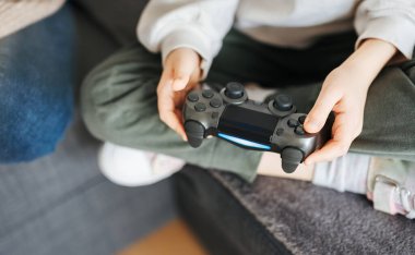 Küçük bir kız elinde oyun kontrolörü video oyunları oynuyor