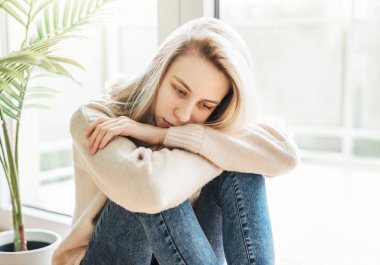 Pencerenin yanındaki üzgün kız bir şey düşünüyor. Stresli kadın kendini yalnız hissediyor