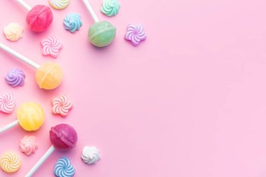 Colorful sweet lollipops and candies over pink background.  Flat lay, top view clipart