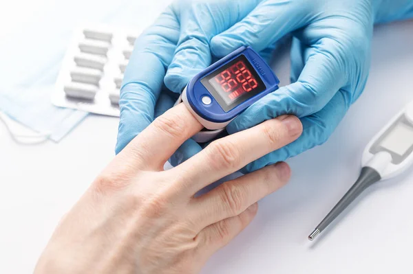 stock image Pulse oximeter measuring oxygen saturation in blood and heart rate.  Pulse oximeter on the patient's hand