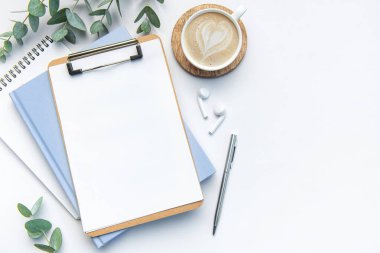 Kahve, defter ve diğer malzemelerle dolu modern beyaz ofis masası. Metin için boş kopyalama alanı. Üst manzara, düz uzanma.