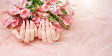 Zarif pastel pembe doğal manikür. Pembe ipek arka planda çiçekli kadın elleri..