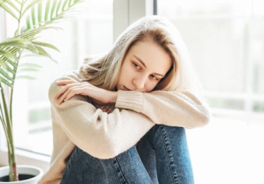 Pencerenin yanındaki üzgün kız bir şey düşünüyor. Stresli kadın kendini yalnız hissediyor