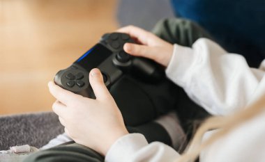 Küçük bir kız elinde oyun kontrolörü video oyunları oynuyor