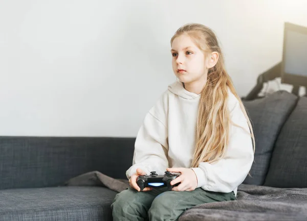 A little girl is playing with a game console at home.