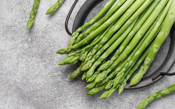 stock image Fresh green asparagus on grey concrete background. Flat lay