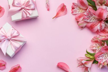 Tebrik metni çerçevesi, Alstroemeria çiçekleri ve pembe arka planda hediye kutuları. Doğal renklerde tebrik kartı. Alstromeria içeren metinler için arka plan. Düz yatış, üst görünüm.