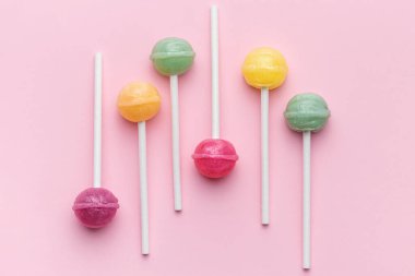 Colorful sweet lollipops over pink background.  Flat lay, top view