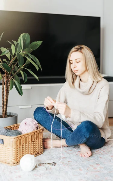 stock image Young woman knitting warm scarf at home