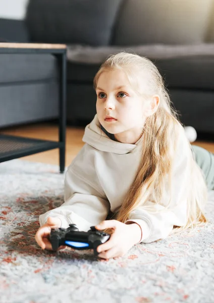 A little girl is playing with a game console at home.