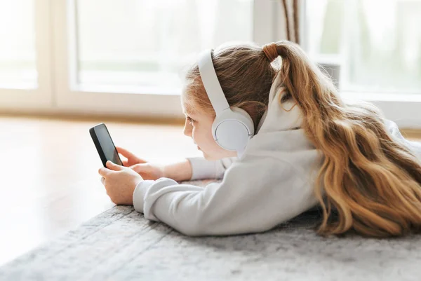 Hymyilevä Pikkutyttö Kuuntelemassa Musiikkia Lattialla — kuvapankkivalokuva