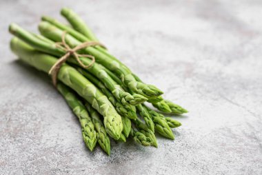 Gri beton arka planda taze yeşil kuşkonmaz. Düz yatıyordu