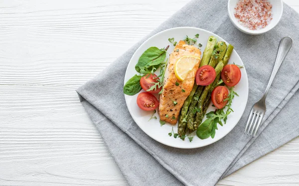 Pişmiş lezzetli somon, yeşil kuşkonmaz ve sebze tabağı. 