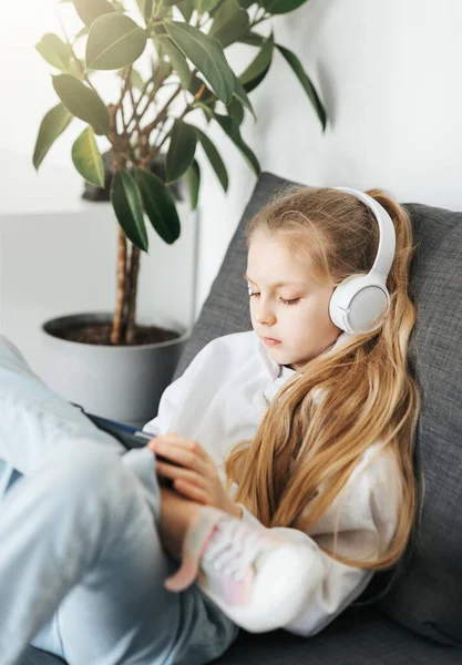Little Girl Lying Couch Electronic Tablet Listens Music White Headphones — Stock Photo, Image