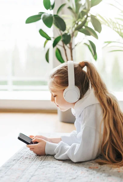 Hymyilevä Pikkutyttö Kuuntelemassa Musiikkia Lattialla — kuvapankkivalokuva