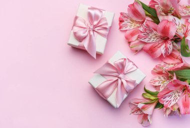 Tebrik metni çerçevesi, Alstroemeria çiçekleri ve pembe arka planda hediye kutuları. Doğal renklerde tebrik kartı. Alstromeria içeren metinler için arka plan. Düz yatış, üst görünüm.