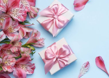 Tebrik metni çerçevesi, Alstroemeria çiçekleri ve mavi arka planda hediye kutuları. Doğal renklerde tebrik kartı. Alstromeria içeren metinler için arka plan. Düz yatış, üst görünüm.