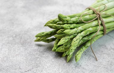 Gri beton arka planda taze yeşil kuşkonmaz. Düz yatıyordu