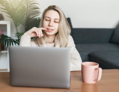 Kredi kartı tutan ve dizüstü bilgisayar kullanan genç bir kadın. İnternette çalışan bir kız. Çevrimiçi alışveriş, internet bankacılığı, evden çalışma 