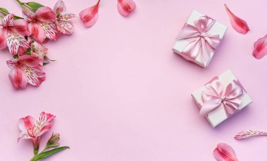 Tebrik metni çerçevesi, Alstroemeria çiçekleri ve pembe arka planda hediye kutuları. Doğal renklerde tebrik kartı. Alstromeria içeren metinler için arka plan. Düz yatış, üst görünüm.
