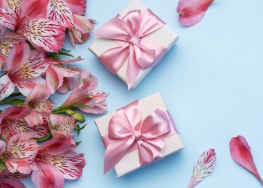 Tebrik metni çerçevesi, Alstroemeria çiçekleri ve mavi arka planda hediye kutuları. Doğal renklerde tebrik kartı. Alstromeria içeren metinler için arka plan. Düz yatış, üst görünüm.