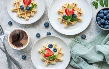 Beton gri arka planda çilek ve yaban mersinli taze pişmiş waffle. Ev yapımı pişirme..