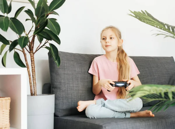 Küçük bir kız evde oyun konsoluyla oynuyor..