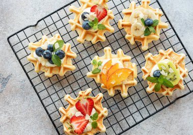 Tekstil arka planında çilek ve yabanmersinli taze pişmiş waffle. Ev yapımı pişirme..