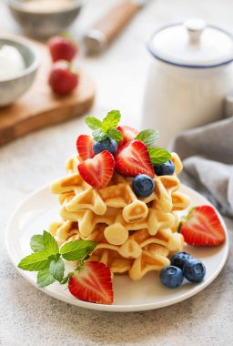 Beton gri arka planda çilek ve yaban mersinli taze pişmiş waffle. Ev yapımı pişirme..