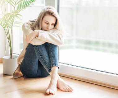 Pencerenin yanındaki üzgün kız bir şey düşünüyor. Stresli kadın kendini yalnız hissediyor