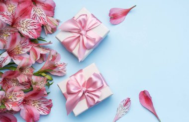 Tebrik metni çerçevesi, Alstroemeria çiçekleri ve mavi arka planda hediye kutuları. Doğal renklerde tebrik kartı. Alstromeria içeren metinler için arka plan. Düz yatış, üst görünüm.