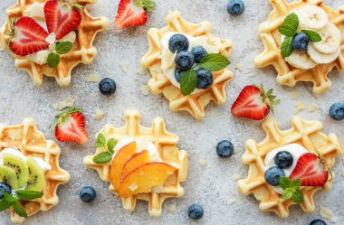 Beton gri arka planda çilek ve yaban mersinli taze pişmiş waffle. Ev yapımı pişirme..